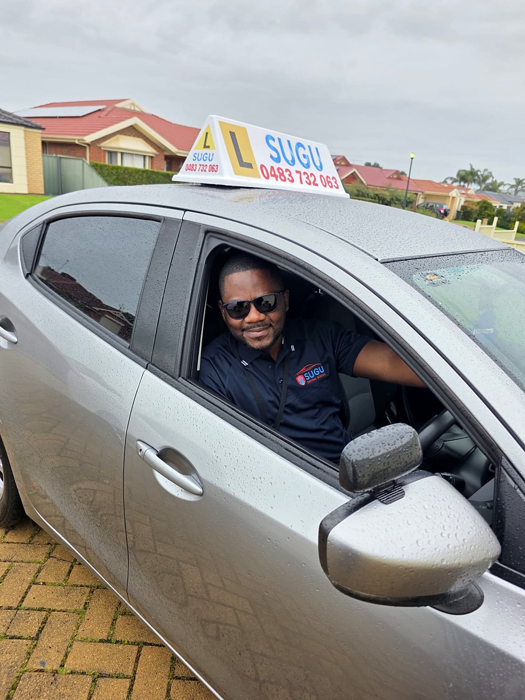 Alex Dieudonne Sugutora beside the Sugu Driving School vehicle
